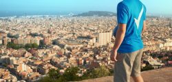 Man in Sure Men t-shirt with football overlooking cityscape